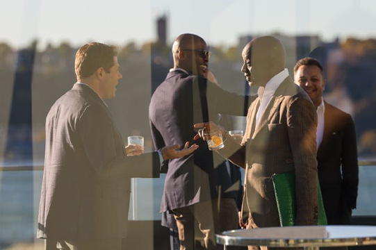 Photo taken through a window of attendees networking outside during HPE NYC 2025 (credit: McDermott Will & Schulte)