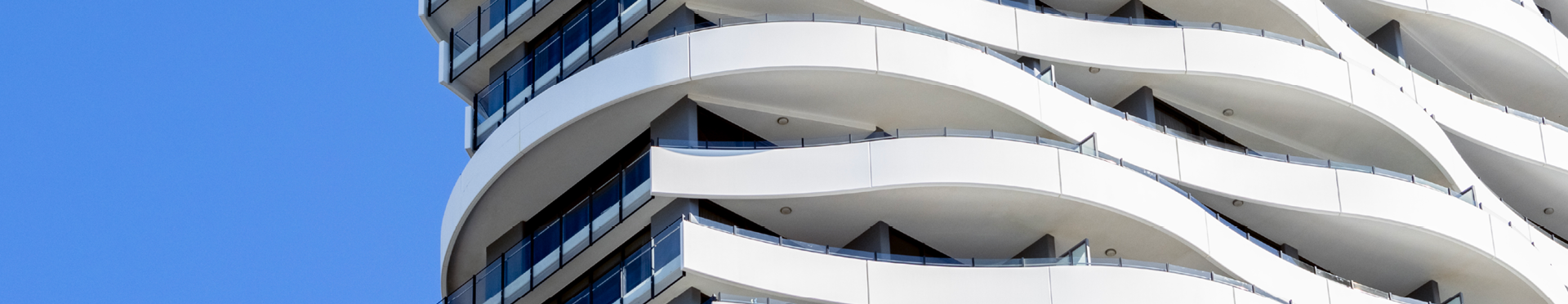 Modern apartment building with curved balconies amid a blue sky backdrop (credit: Getty Images)